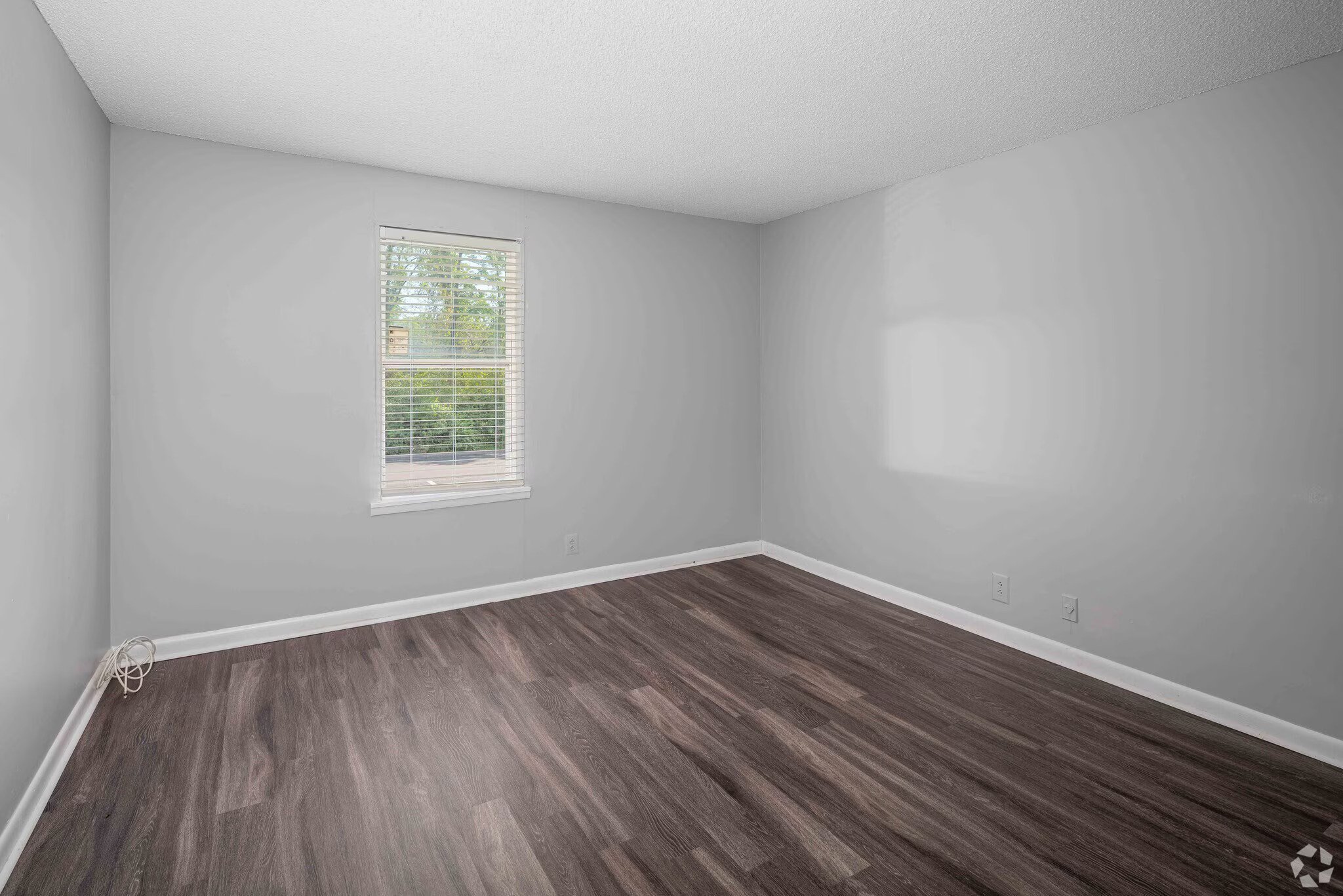 A room with a window and wooden flooring.